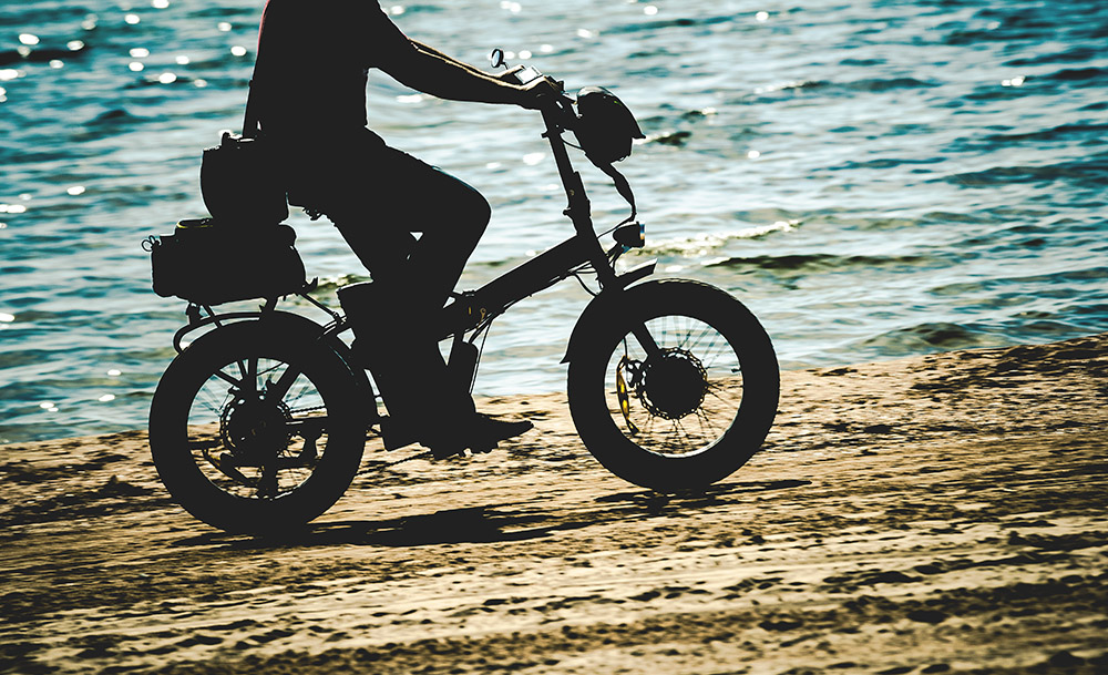 an image of an electric bike on a beach by the sea - perfect for stowing away on a private jet, and using to explore the surroundings